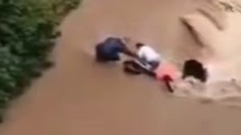 洪水来袭路人带车紧趴岸边求救 男子涉水冒险拉起 下一秒车被卷走